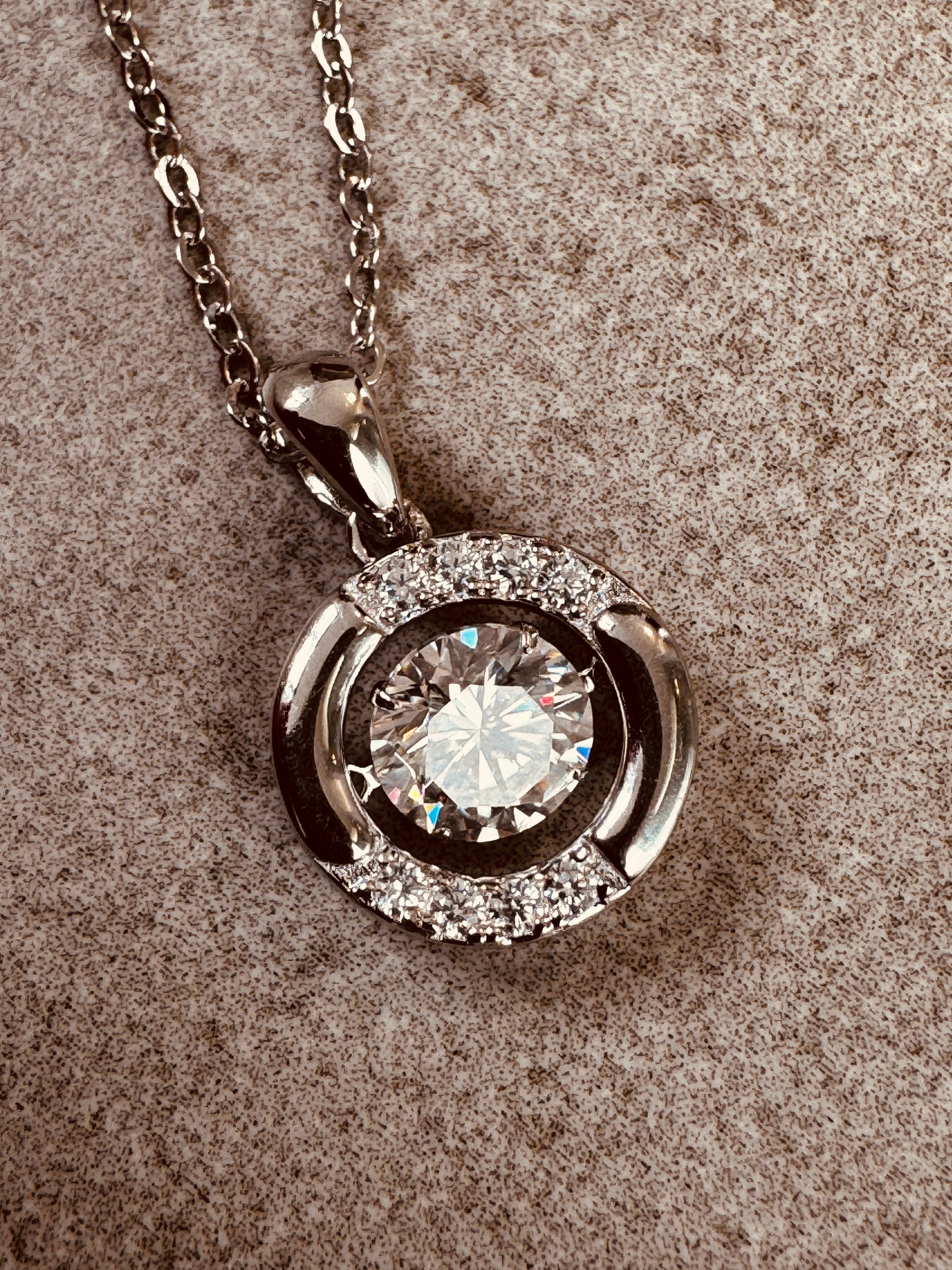 moissanite pendant necklace on a textured surface