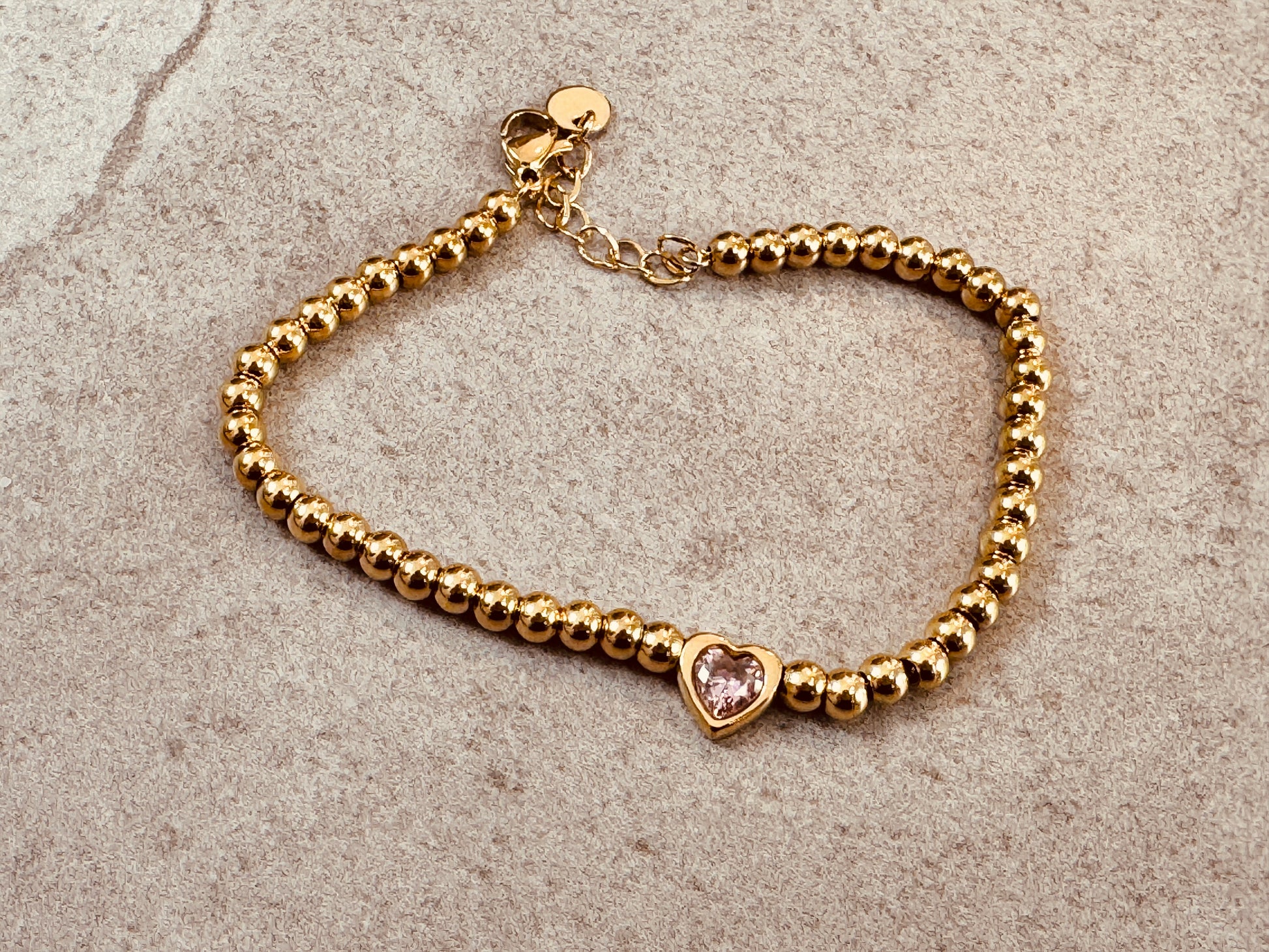 Gold bracelet with a heart-shaped pink gemstone 